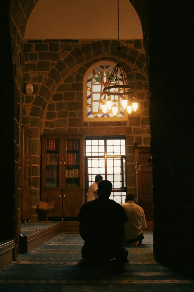 Men praying inside a beautifully lit mosque, reflecting faith and serenity.