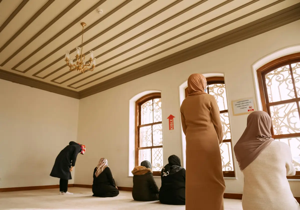 Women engaged in prayer inside a mosque in İstanbul, showcasing Muslim culture and spirituality.